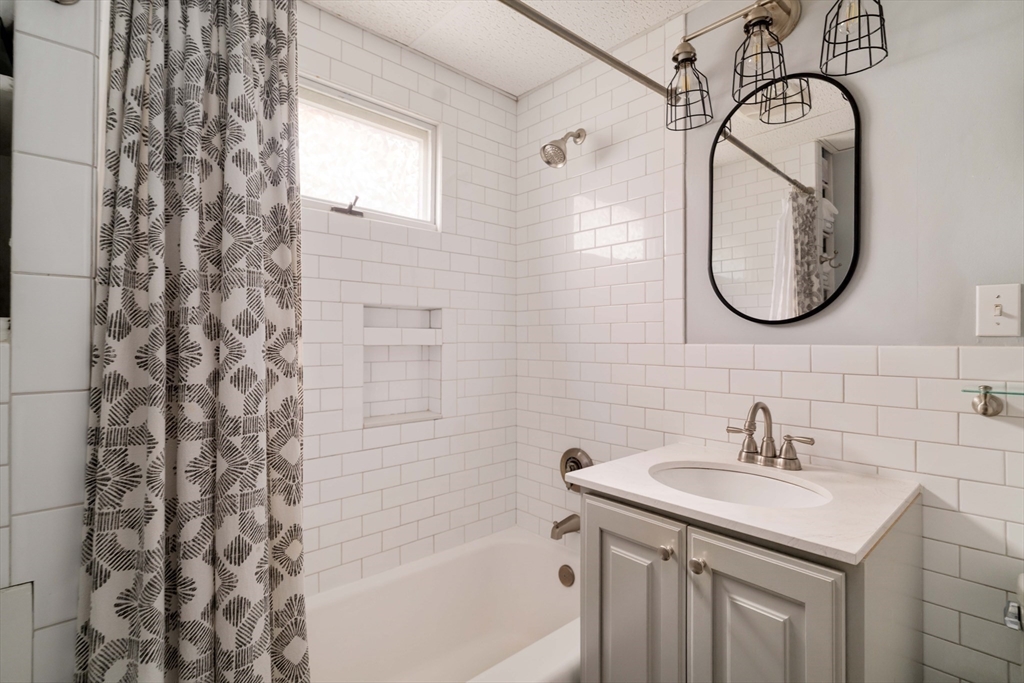 250 Poplar Street, Unit 1 Boston, MA 02131 - Photo 27 of 34 a bathroom with a sink a mirror a vanity and a bathtub