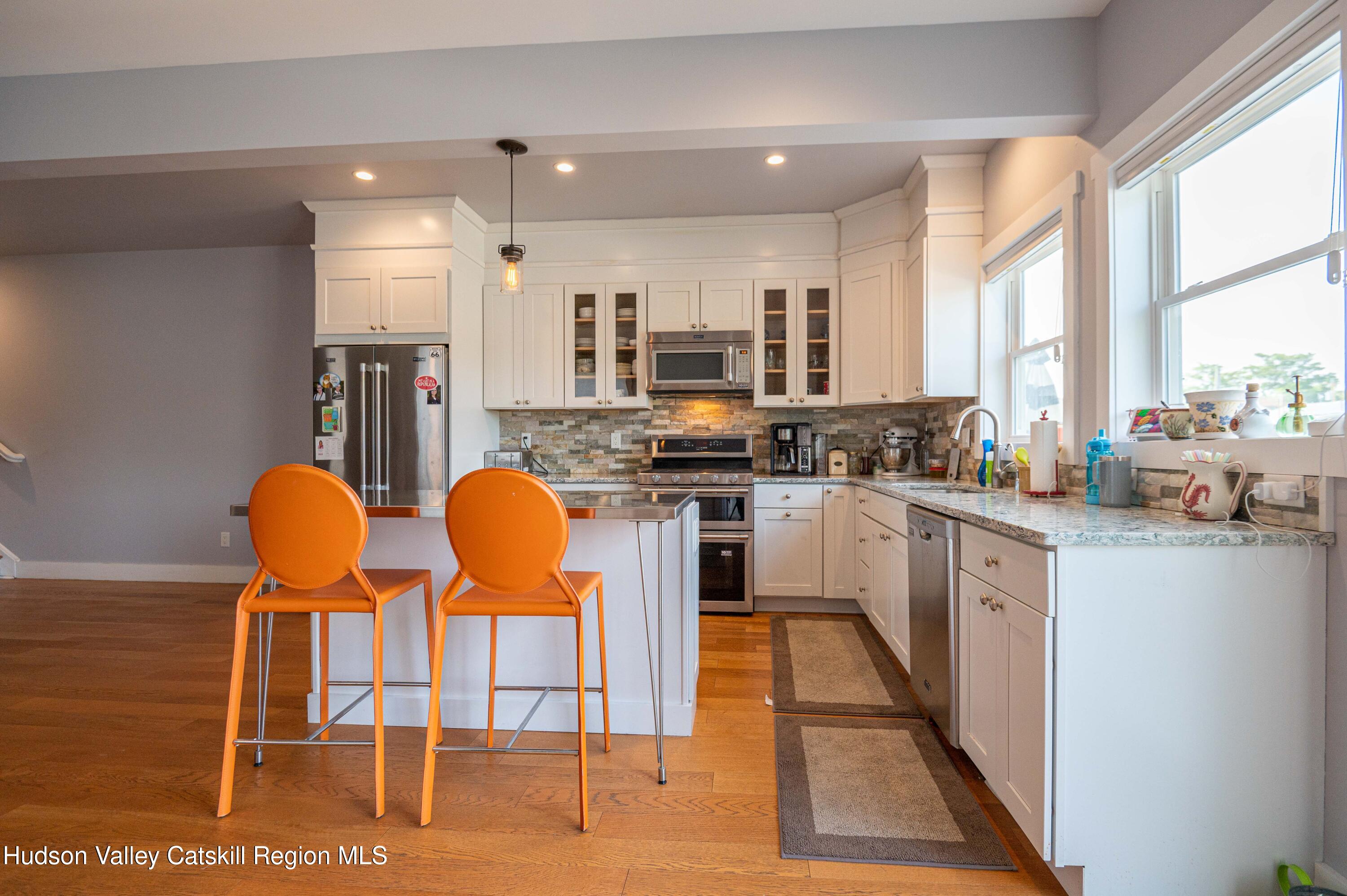 225 State Street, Unit RIGHT Hudson, NY 12534 - Photo 11 of 29 a kitchen with stainless steel appliances kitchen island granite countertop a table and chairs in it