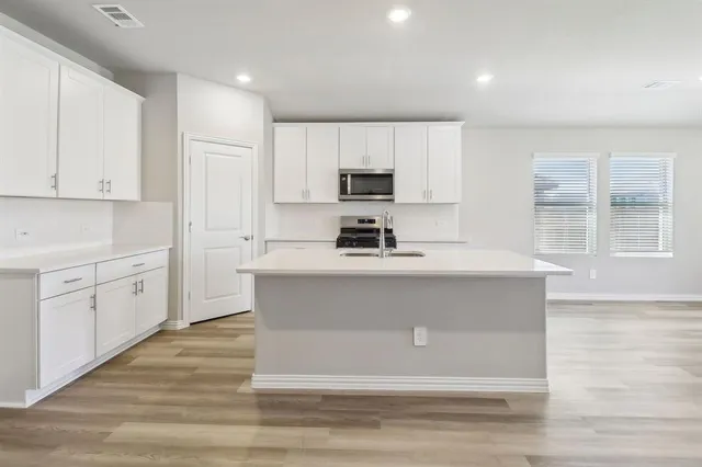 a kitchen with white cabinets and window