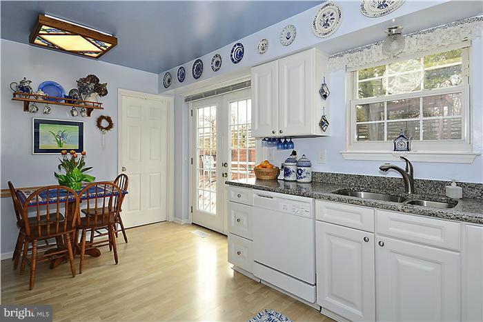 14424 Basingstoke Lane Silver Spring, MD 20905 - Photo 10 of 29 a kitchen with granite countertop a dining table chairs and white cabinets next to a window