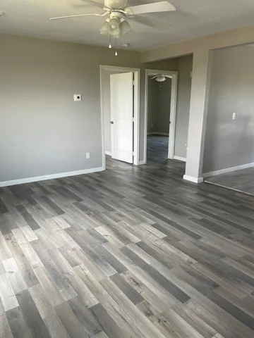 en empty room with wooden floor and fan