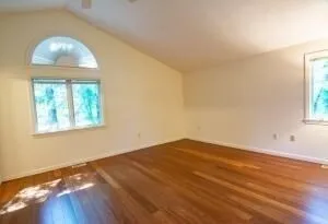 an empty room with wooden floor and windows