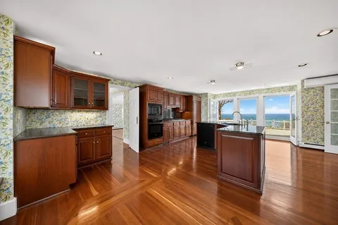 a kitchen with stainless steel appliances granite countertop a refrigerator a stove top oven and a sink with wooden floor