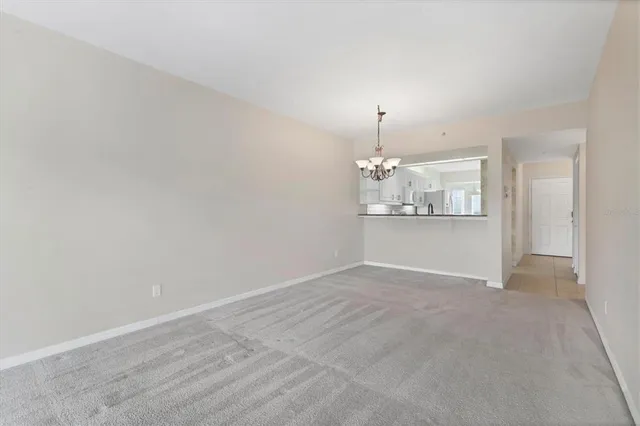 an empty room with chandelier fan and windows