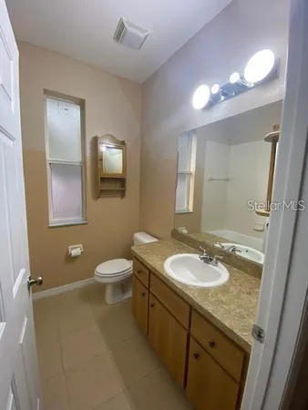 a bathroom with a granite countertop sink a toilet a mirror and shower