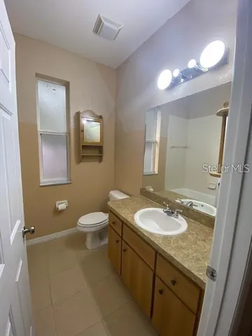 a bathroom with a granite countertop sink a toilet a mirror and shower