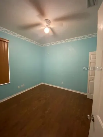 an empty room with a fan & a window