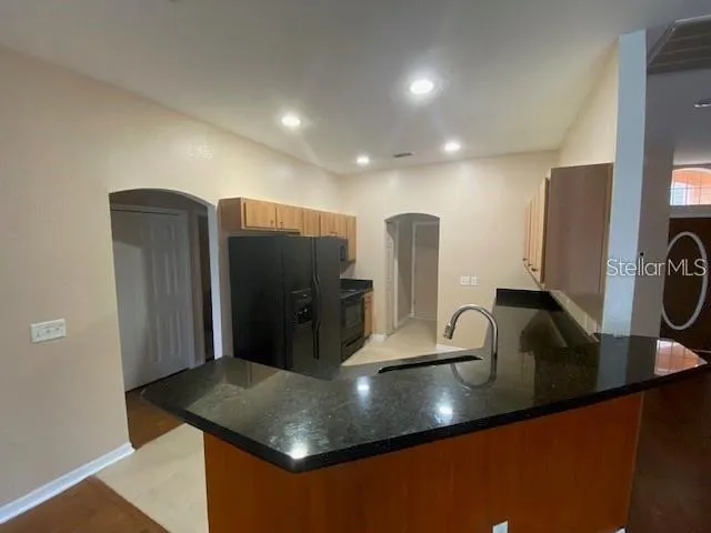 a kitchen with stainless steel appliances granite countertop a sink a refrigerator and a stove