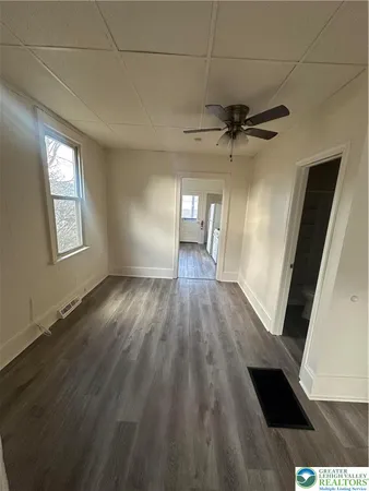 a view of empty room with wooden floor and fan