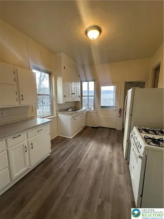 a kitchen with wooden floors and white cabinets
