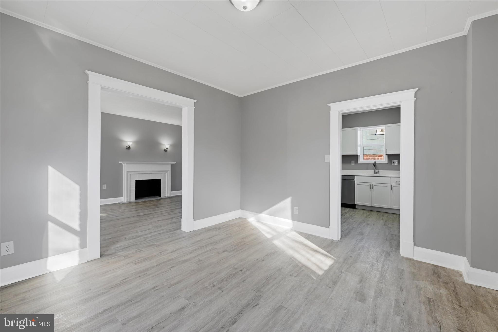 6113 Sefton Avenue Baltimore, MD 21214 - Photo 8 of 25 a view of an empty room with wooden floor and a kitchen