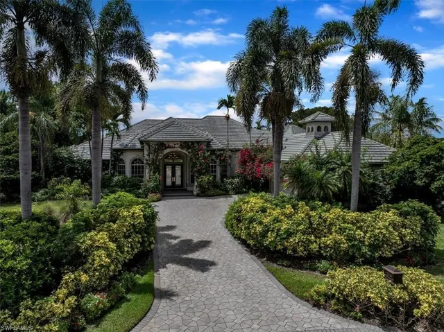 a front view of a house with a yard and potted plants