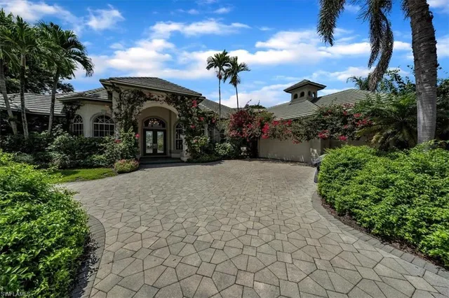 a front view of a house with a yard and potted plants