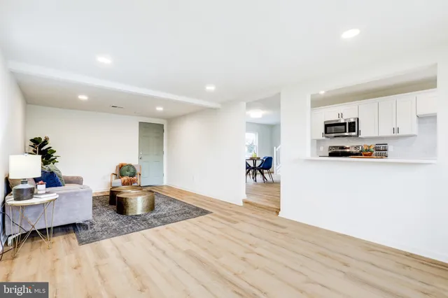 a living room with furniture wooden floor and a kitchen view