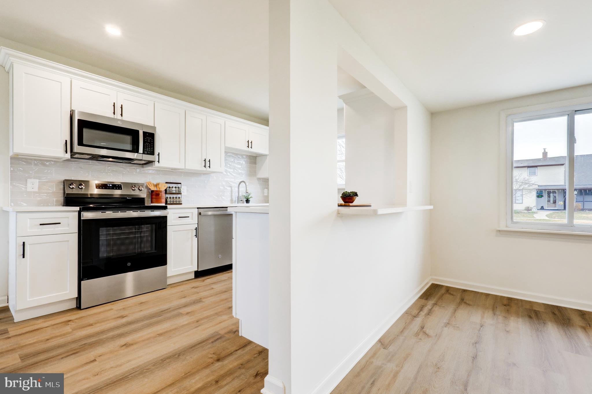 31 Nature Lane Levittown, PA 19054 - Photo 5 of 33 a kitchen with stainless steel appliances white cabinets and wooden floor