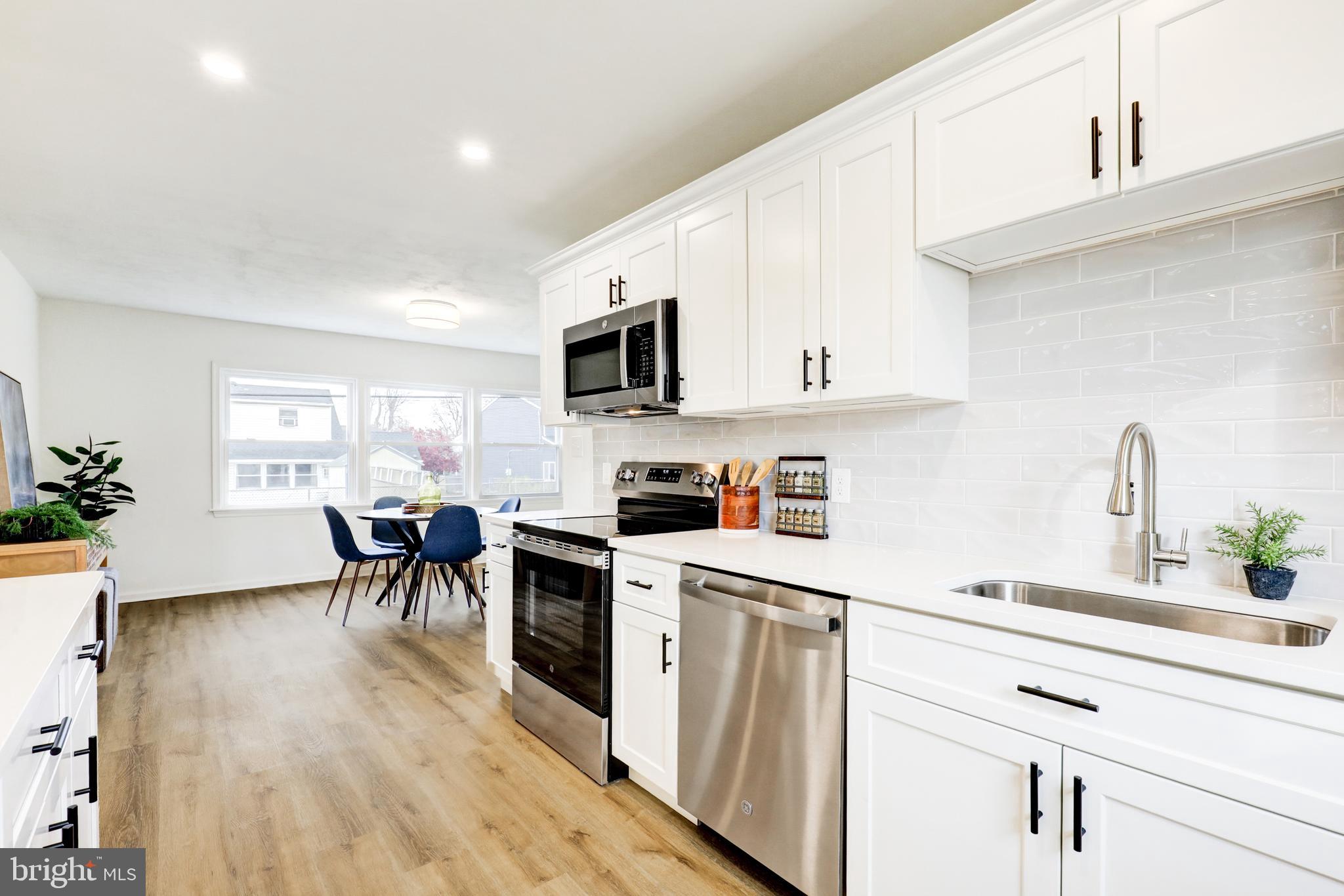 31 Nature Lane Levittown, PA 19054 - Photo 7 of 33 a kitchen with stainless steel appliances a white table chairs and a refrigerator