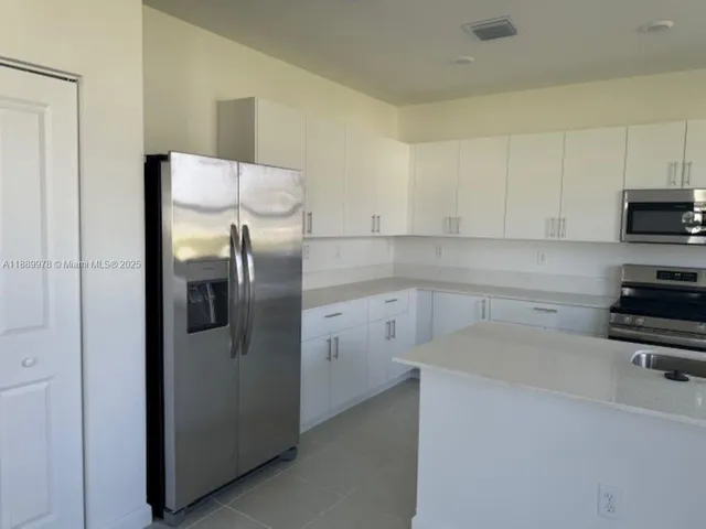 a kitchen with a refrigerator sink and cabinets