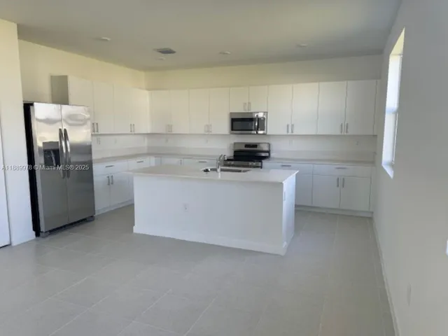 a kitchen with stainless steel appliances a refrigerator sink and white cabinets