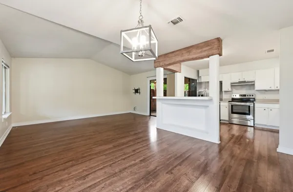 a view of a kitchen and an empty room with wooden floor