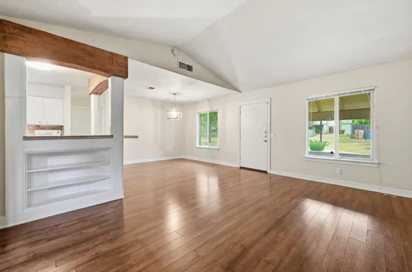 an empty room with wooden floor and windows