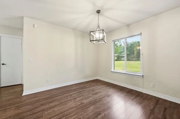 a view of empty room with wooden floor fan and window