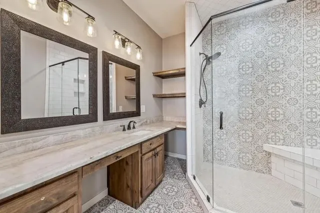 a bathroom with a granite countertop double vanity sink mirror and shower