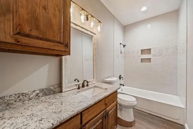 a bathroom with a granite countertop sink toilet and shower