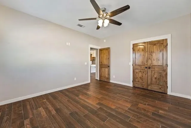 an empty room with wooden floor and a ceiling fan
