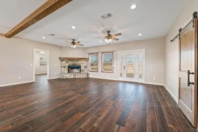 an empty room with wooden floor fireplace and windows