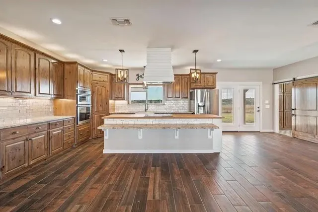 a large kitchen with granite countertop a large counter top stainless steel appliances and cabinets