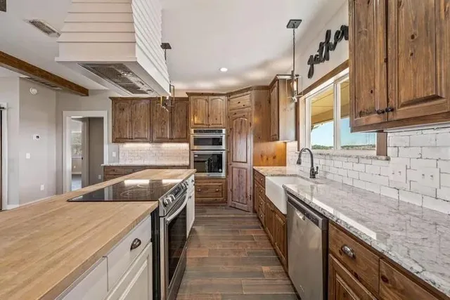 a kitchen with granite countertop a sink and stainless steel appliances