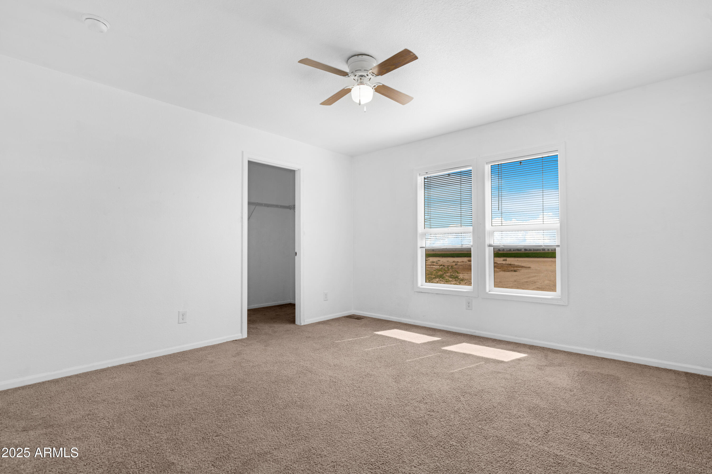 4318 North White Road Maricopa, AZ 85139 - Photo 11 of 21 an empty room with a ceiling fan and windows