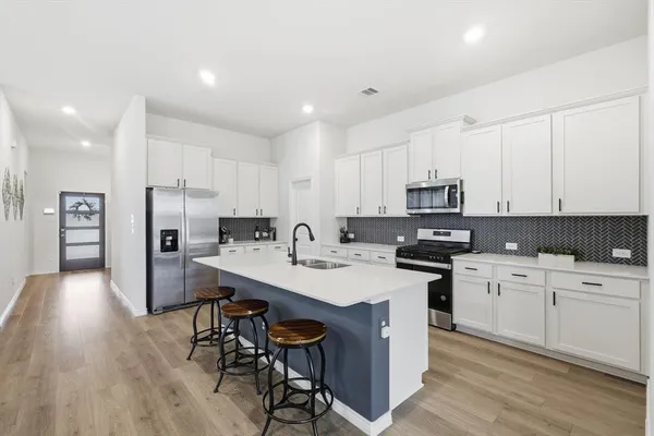 a kitchen with a sink a counter top stainless steel appliances and cabinets
