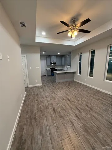 an empty room with a ceiling fan and wooden floor
