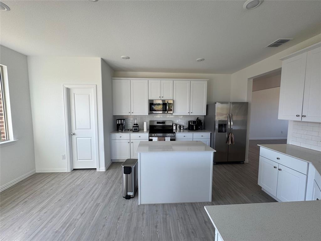 4905 Sagerun Drive Princeton, TX 75407 - Photo 11 of 25 a kitchen with stainless steel appliances granite countertop a refrigerator a stove top oven a sink and dishwasher with wooden floor