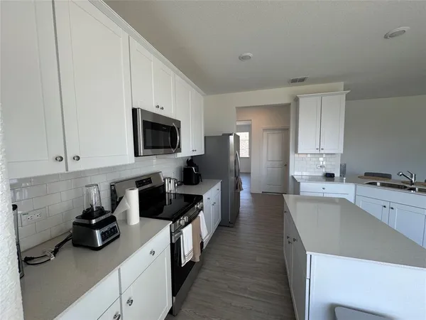a kitchen with a center island wooden floor and stainless steel appliances