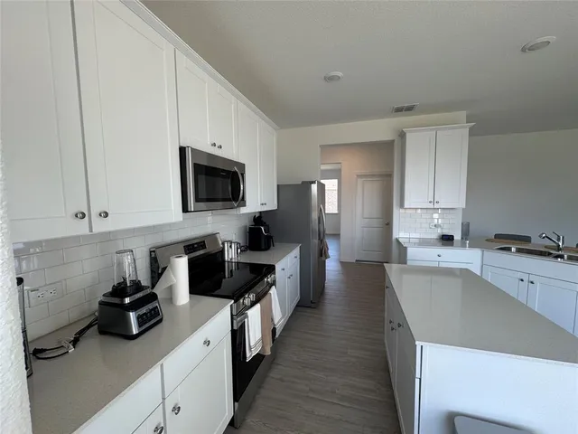 a kitchen with a center island wooden floor and stainless steel appliances