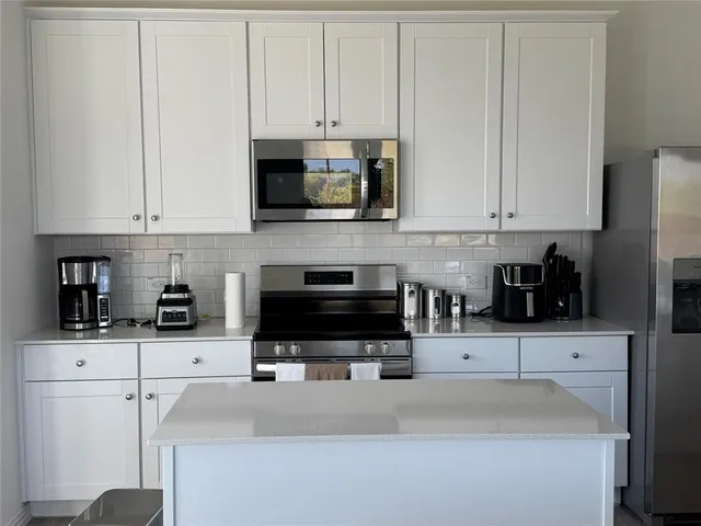 a kitchen with stainless steel appliances granite countertop a refrigerator a stove top oven a sink and dishwasher with wooden floor