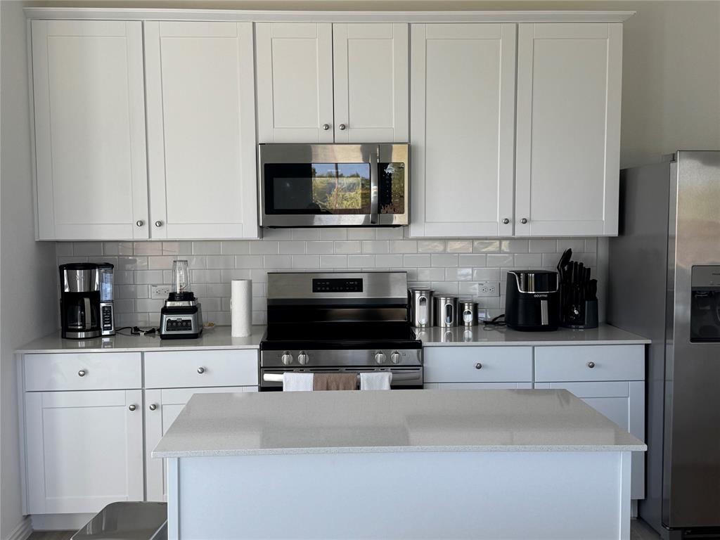 4905 Sagerun Drive Princeton, TX 75407 - Photo 10 of 25 a kitchen with stainless steel appliances granite countertop a stove a sink and white cabinets