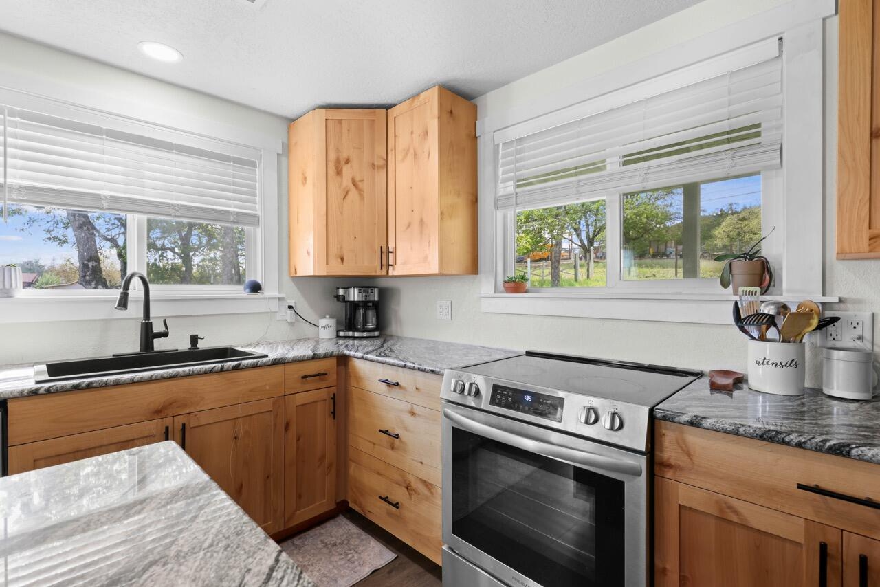 380 Greenleaf Drive Eagle Point, OR 97524 - Photo 15 of 31 a kitchen with stainless steel appliances granite countertop a sink stove and window
