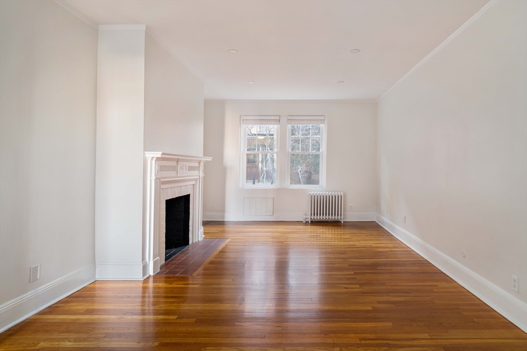 321 Tappan Street, Unit 1 Brookline, MA 02445 - Photo 5 of 19 a view of empty room with wooden floor and fireplace