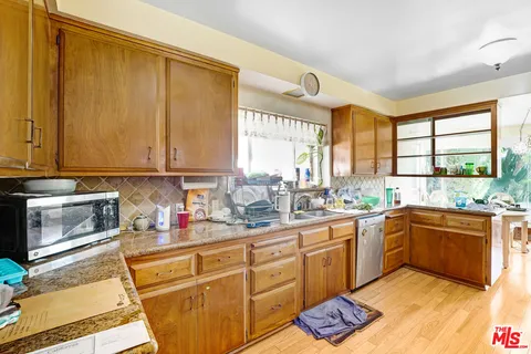 a kitchen with stainless steel appliances a stove top oven a refrigerator a sink dishwasher and cabinets with wooden floor