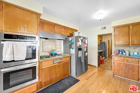 a kitchen with stainless steel appliances wooden floor and a large window