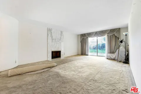 a view of an empty room with a fireplace and a window
