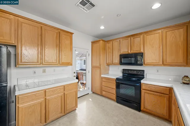 a kitchen with stainless steel appliances granite countertop a stove a sink dishwasher and a refrigerator with white cabinets