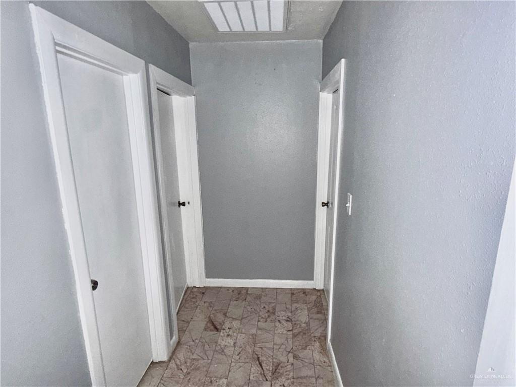 204 Ramon Private Road Mission, TX 78572 - Photo 7 of 11 Hallway featuring light gray walls, white trim, and patterned flooring