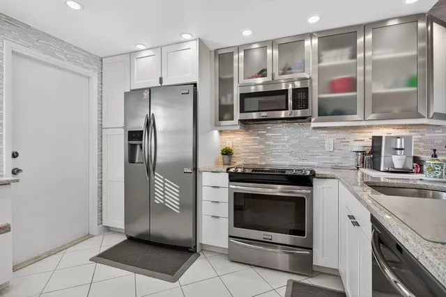 a kitchen with stainless steel appliances granite countertop a refrigerator and a sink
