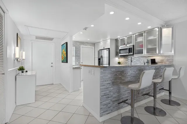 a kitchen with stainless steel appliances kitchen island granite countertop a refrigerator and a sink