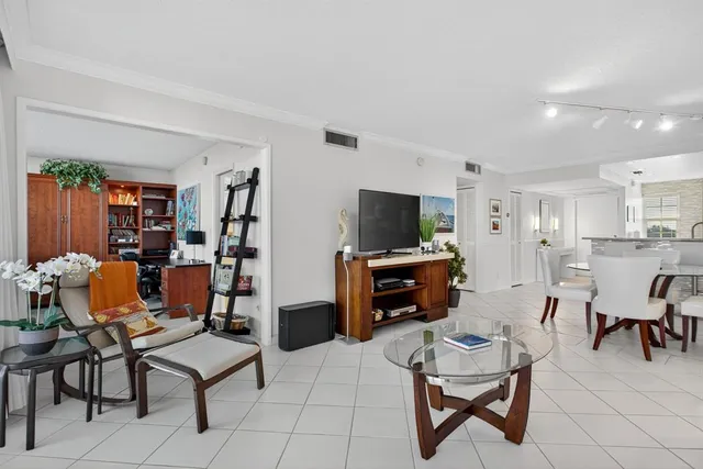 a living room with furniture a flat screen tv and kitchen view