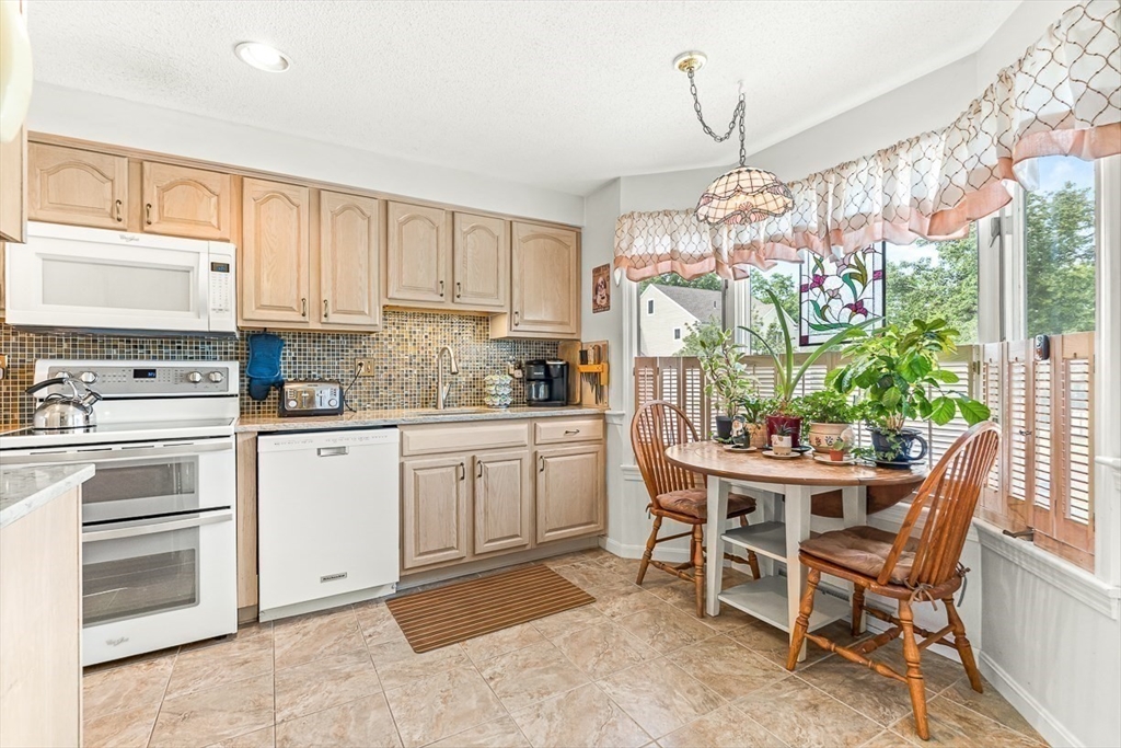 112 Abington Road, Unit 112 Danvers, MA 01923 - Photo 6 of 38 a kitchen with stainless steel appliances kitchen island granite countertop a table and chairs in it
